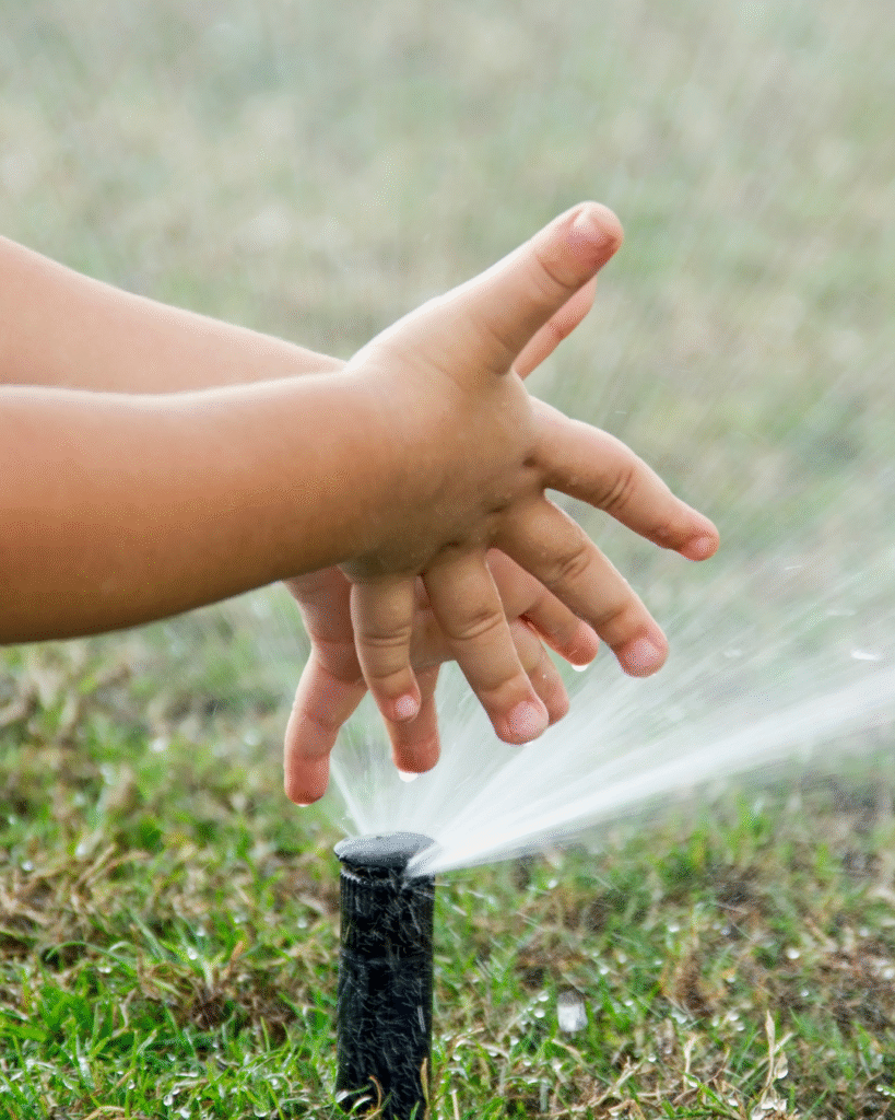 A kid playing in water-efficient sprinkler system designed for Colorado landscapes